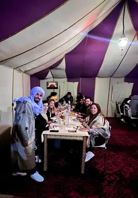 a group of people sitting around a table in a tent at Merzouga Formidable camp in Merzouga