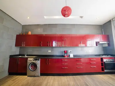 a kitchen with red cabinets and a washing machine at Villa privée & élégante avec piscine & jardin in Marrakech