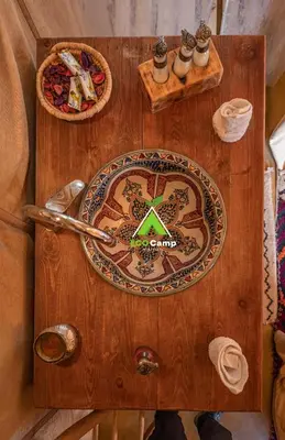 a wooden table with a plate of food on it at Eco Desert Camp in Merzouga