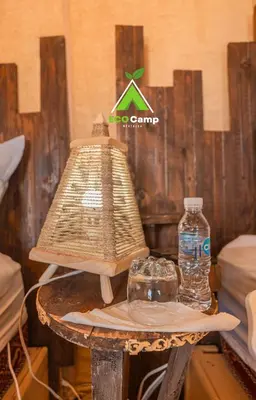 a table with a lamp and water bottles on it at Eco Desert Camp in Merzouga