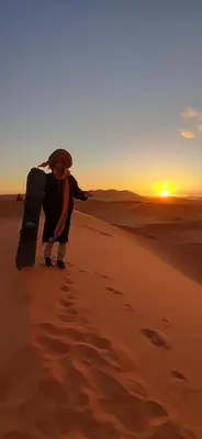 a man is walking through the desert with at Sahara 4Seasons Appartement in Merzouga