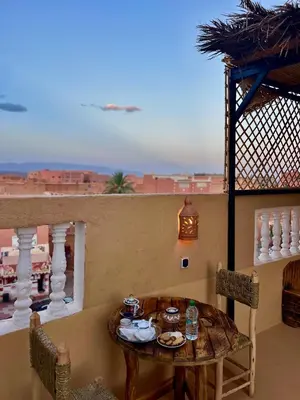 a table and chairs on a balcony with a view of the desert at Riad Dar Sahara - Panoramic Rooftop in Nkob