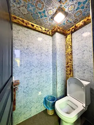 a bathroom with a toilet and a blue tiled wall at Riad Dar Sahara - Panoramic Rooftop in Nkob