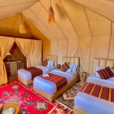 a group of four beds in a tent at Aurea Duna Luxury Camp in Merzouga
