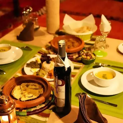 a table with a bottle of wine and plates of food at Aurea Duna Luxury Camp in Merzouga