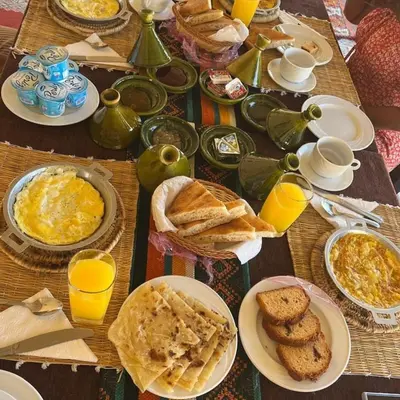 a table topped with plates of breakfast food and orange juice at Aurea Duna Luxury Camp in Merzouga