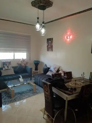 a living room with a blue couch and a table at Appartement lux in Fès
