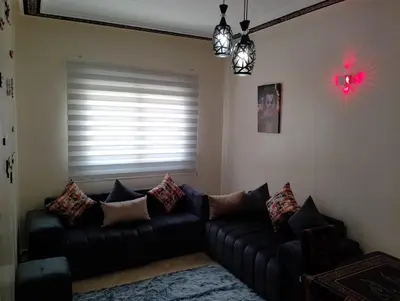 a living room with a black couch and a window at Appartement lux in Fès
