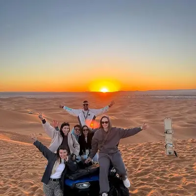 a group of people posing for a picture in the desert at Spectacular Luxury Camp in Merzouga