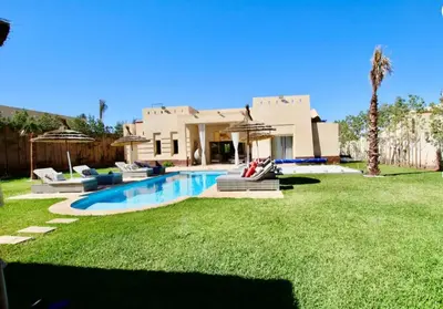 a house with a swimming pool in front of a yard at Sublime Villa Piscine & Jacuzzi in Marrakech