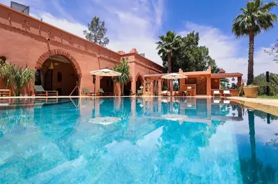 a swimming pool with blue water in front of a building at Dar des gazelles kech in Oulad Abbou