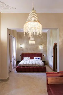 a bedroom with a large bed and a chandelier at Dar des gazelles kech in Oulad Abbou