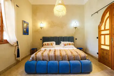 a bedroom with a large bed with a blue ottoman at Dar des gazelles kech in Oulad Abbou