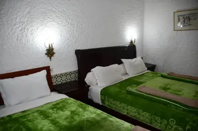 a hotel room with two beds with green sheets at Hôtel Rose Mgouna in Kalaat MGouna