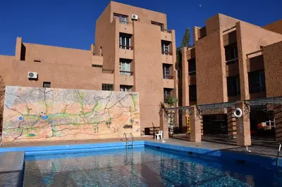 a swimming pool in front of two buildings with a map at Hôtel Rose Mgouna in Kalaat MGouna