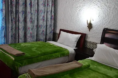 a bedroom with two beds with green sheets at Hôtel Rose Mgouna in Kalaat MGouna