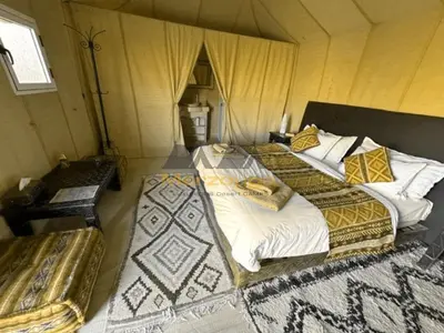 a bedroom with two beds and a table in a room at Merzouga Chic Luxury Camps in Merzouga