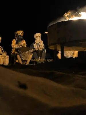 two statues of people wearing masks sitting next to a grill at Merzouga Chic Luxury Camps in Merzouga