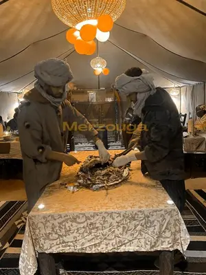 two women preparing food on a table in a tent at Merzouga Chic Luxury Camps in Merzouga