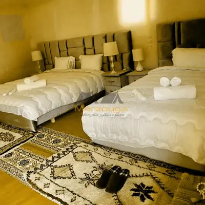 a bedroom with two beds and a rug at Merzouga Chic Luxury Camps in Merzouga