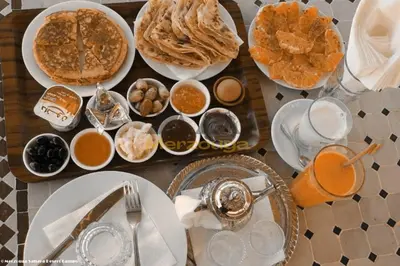 a table topped with plates of food and drinks at Merzouga Chic Luxury Camps in Merzouga