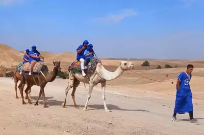 a group of people riding on the backs of camels in the desert at Erg Chebbi Desert Glamping in Merzouga