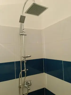 a shower in a bathroom with blue and white tiles at Appartement Fadila in Fès