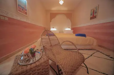 a bedroom with a bed and a rattan chair at Palm View Palace in Ouarzazate