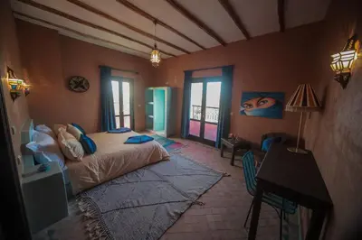 a bedroom with a bed and a desk and windows at Palm View Palace in Ouarzazate