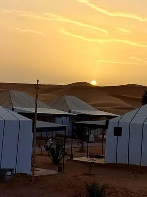a group of tents in the desert at sunset at Merzouga sultana luxury tent in Merzouga
