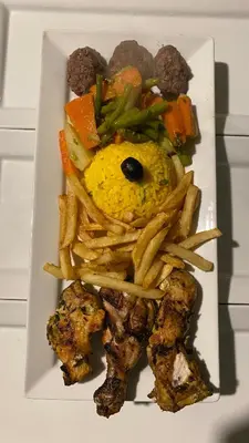 a plate of food with french fries and meat at Merzouga sultana luxury tent in Merzouga