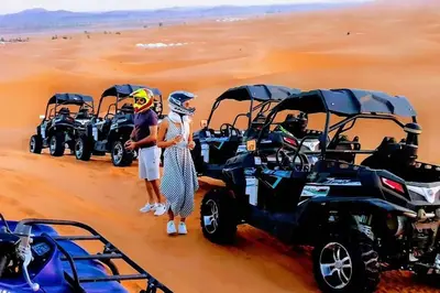 a group of people standing in the desert with atvs at Merzouga Glossy Camp in Merzouga