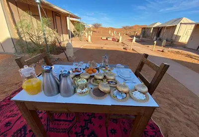 a table with food and utensils on top at Merzouga Glossy Camp in Merzouga