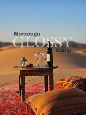 a table with two glasses and a bottle of wine at Merzouga Glossy Camp in Merzouga