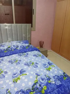 a bed with a blue comforter with blue flowers at Appartement in Fès