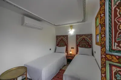 a bedroom with two beds and a table in it at Dar Amazigh in Fès