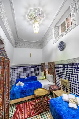 a bedroom with two beds and a table at Dar Amazigh in Fès