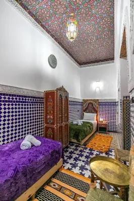 a bedroom with two beds and a ceiling covered in colorful tiles at Dar Amazigh in Fès