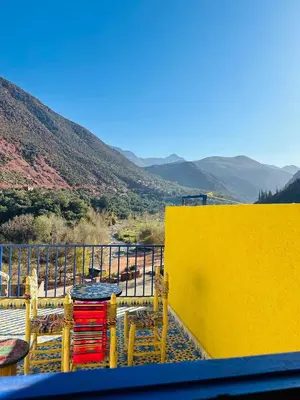 a yellow wall with tables and chairs on a balcony at Maison Berber in Ourika