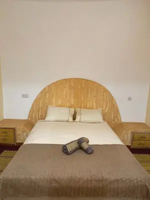 a wooden bed with a tie laying on it at Hôtel Khalwa in Jenane Sidi Amer