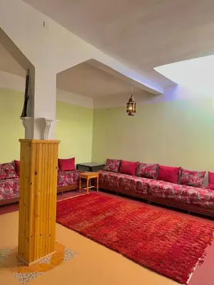 a living room with a red couch and a red rug at Hôtel Khalwa in Jenane Sidi Amer