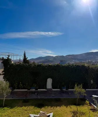 a view of a garden with benches and a hedge at Hôtel Khalwa in Jenane Sidi Amer