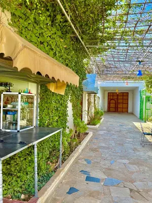 a building with a green ivy covered wall with a table at Hôtel Khalwa in Jenane Sidi Amer