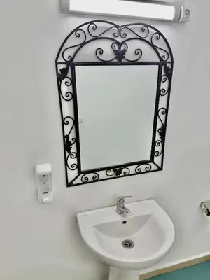 a bathroom with a mirror above a sink at Hôtel Khalwa in Jenane Sidi Amer