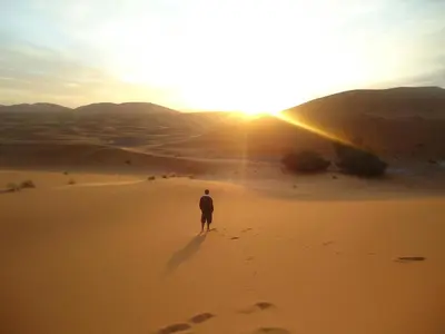 a man standing in the desert watching the sunset at bed&breakfast in Merzouga