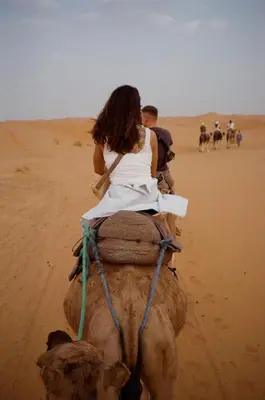 a woman riding on the back of a camel in the desert at bed&breakfast in Merzouga