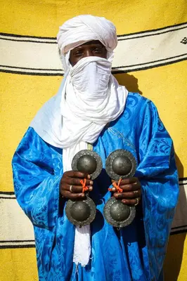 a man in a blue raincoat holding objects in his hands at bed&breakfast in Merzouga