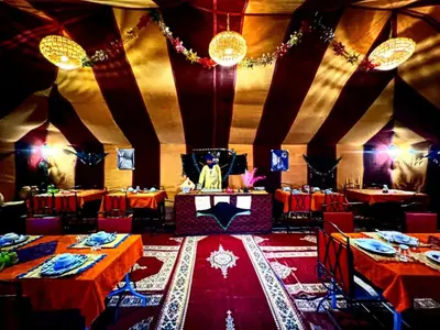 a dining room with red tables and chairs and a room with red table cloth at Private Luxury Camp in Merzouga