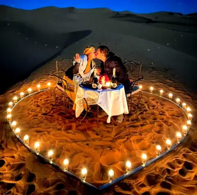 a group of people sitting at a table with lights at Private Luxury Camp in Merzouga