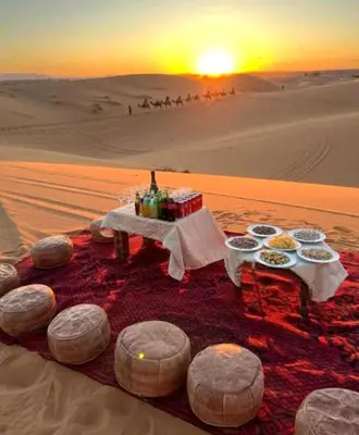 a table in the middle of the desert with food at Private Luxury Camp in Merzouga